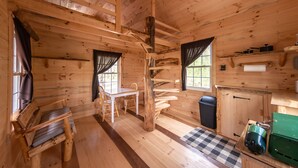 A wooden cabin interior with a dining area, a staircase, and a small kitchenette. - Dogwood Cabin - Off Grid (Chesterhill)