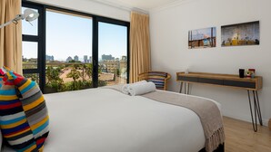 A hotel room with a large bed, a desk, and a view of the city. - Burnside 302 (Cape Town)