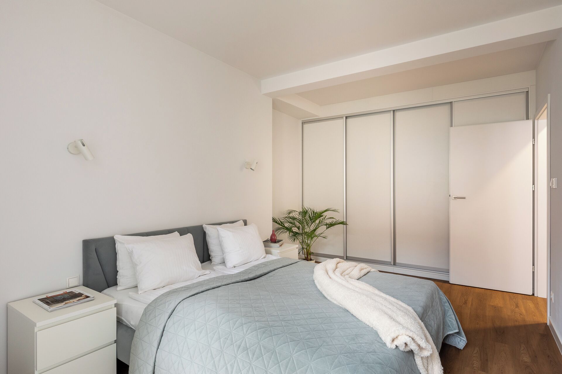 A modern bedroom with a bed, bedside table, and a wardrobe.