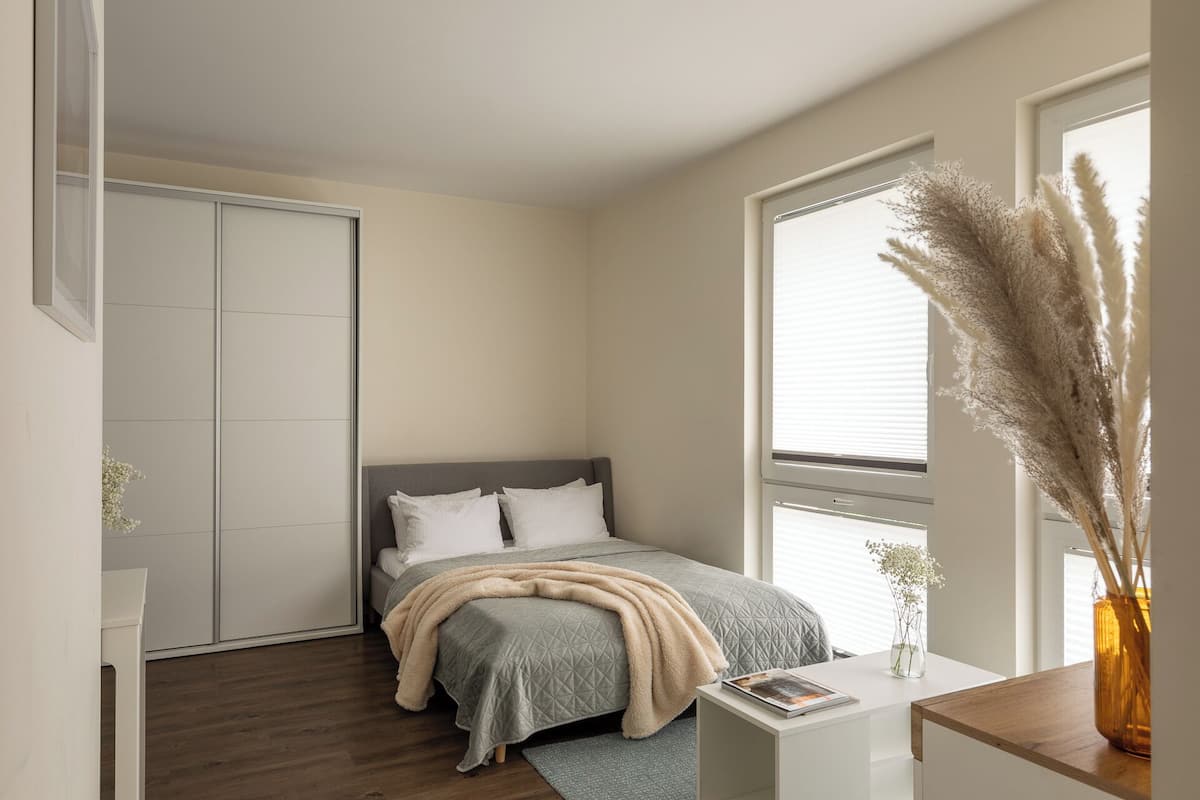 Un dormitorio con cama, mesita de noche y ventana con vista a pastos de pampa.
