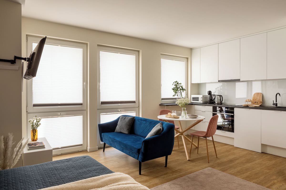 Un apartamento moderno con sala de estar que incluye un sofá azul y comedor con una mesa pequeña y sillas.