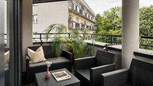 A balcony with wicker furniture, a potted plant, and a magazine on a table. - Trevi Apartments Tychy (Tychy)