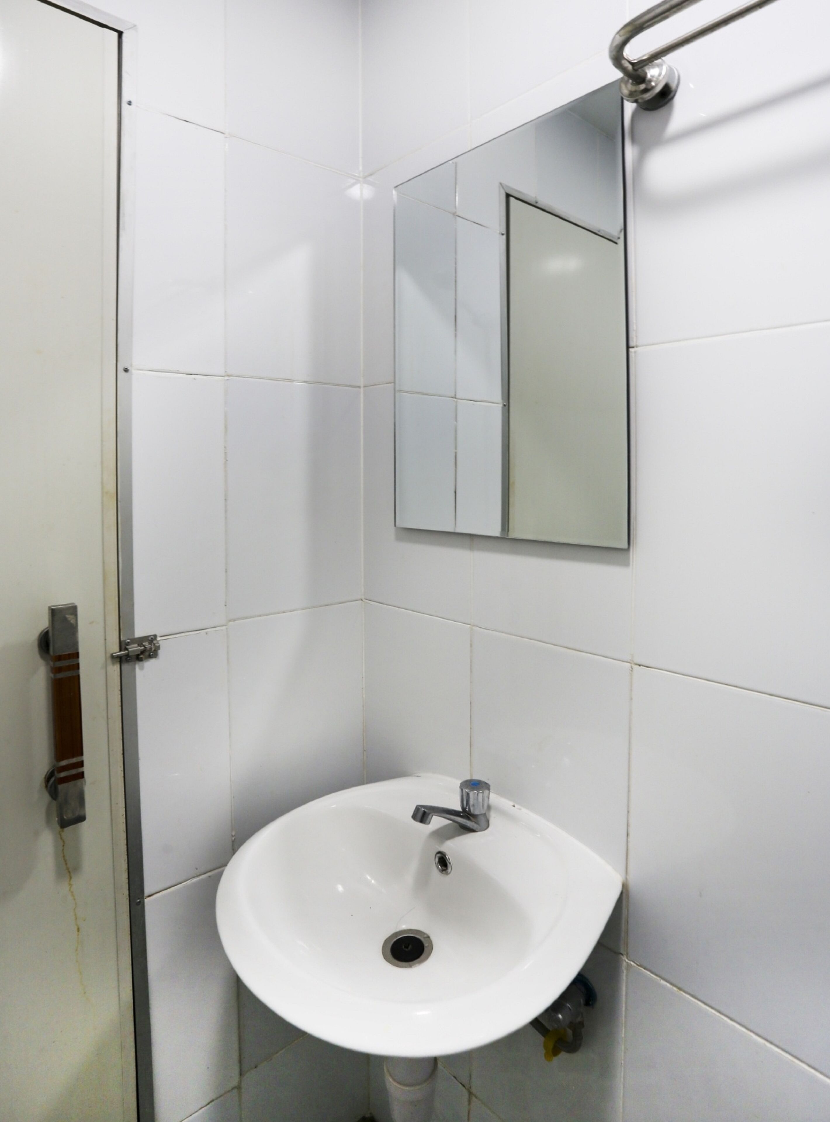 A bathroom with a white sink, a mirror, and a door.