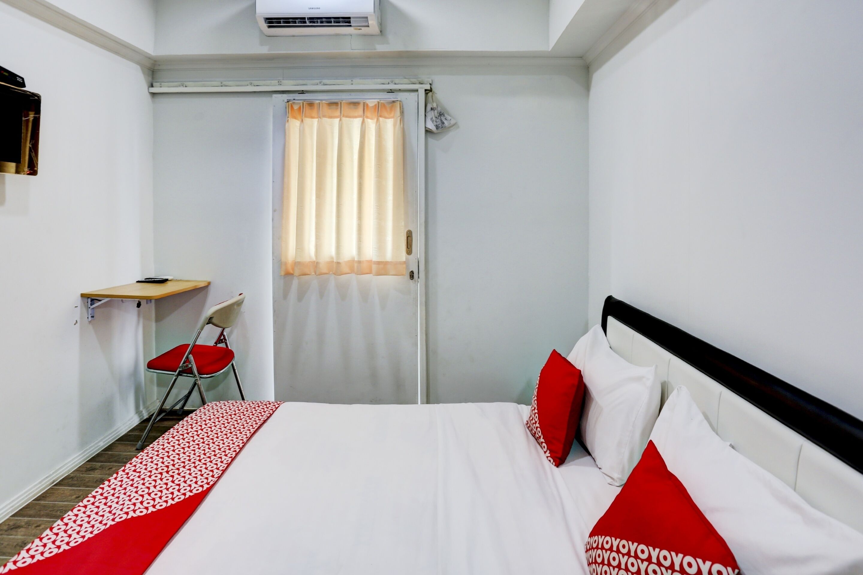 Une chambre d’hôtel avec un lit, un bureau, une chaise et une fenêtre avec des rideaux.