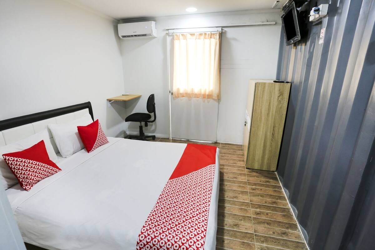 Une chambre d’hôtel équipée d’un lit, d’un bureau, d’une chaise, d’un climatiseur, d’une télévision et d’une armoire.