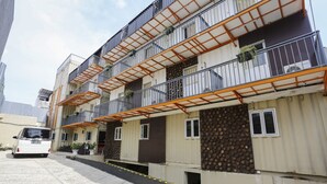 A multi-story residential building with balconies, a car parked in front, and a gated entrance. - Capital O 3300 Nadjara Residence Syariah (Pekanbaru)