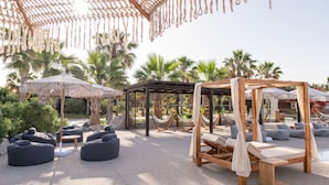 Un resort con hamacas, pufs y una estructura de madera tipo dosel.