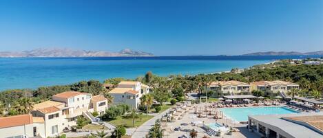 A resort with a pool, multiple buildings, and a view of the sea.