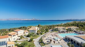 Un resort con piscina, varias edificaciones y vista al mar.