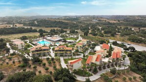 Un resort con varias edificaciones, una piscina y un paisaje montañoso al fondo.