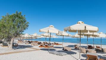 Een privéstrand, ligstoelen aan het strand, parasols