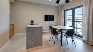 Een moderne keuken met een flatscreen televisie, een eethoek met een ronde tafel en stoelen, en een groot raam met uitzicht op de stad.