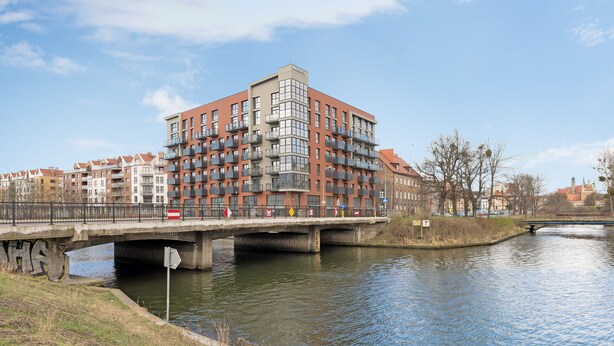 Een meerlaags gebouw met balkons, een brug en een gracht.