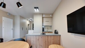 Een moderne keuken met een houten kookeiland, twee hanglampen en een ingebouwde televisie.