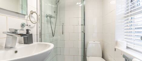 A modern bathroom with a glass-enclosed shower, a white sink, and a toilet.