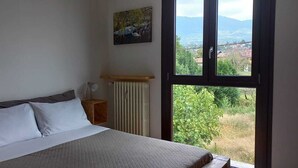 Een slaapkamer met een bed, een raam, een radiator en een schilderij aan de muur.