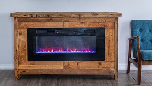A living room with a fireplace, a mounted television, and a blue upholstered chair.