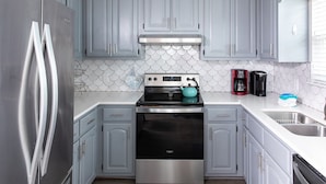 A modern kitchen with grey cabinets, stainless steel appliances, and a tiled backsplash.