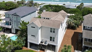 Un quartier résidentiel avec des maisons situées près d’une plage, comprenant une grande maison avec un garage et une plus petite maison dotée d’un balcon.