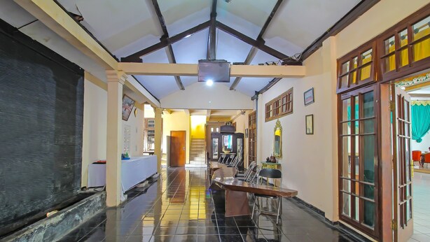 A corridor with a tiled floor, a reception desk, and a door with curtains. - OYO 1984 Hotel Istana Family Syariah (Nganjuk)