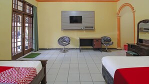 A hotel room with two beds, a desk, a TV mounted on the wall, and a window with curtains. - OYO 1984 Hotel Istana Family Syariah (Nganjuk)