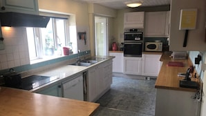 A kitchen with white cabinets, a wooden countertop, a sink, a stove, and a microwave.