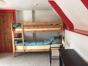 Un letto a castello con una scrivania e una sedia, una porta rossa e un soffitto bianco.