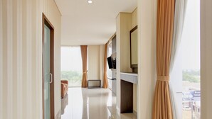 A hotel corridor with a view to the outside, a flat-screen TV mounted on the wall, and a door with a handle.