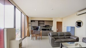 A modern living room with a leather sofa, a glass coffee table, and a dining area with a wooden table and chairs.