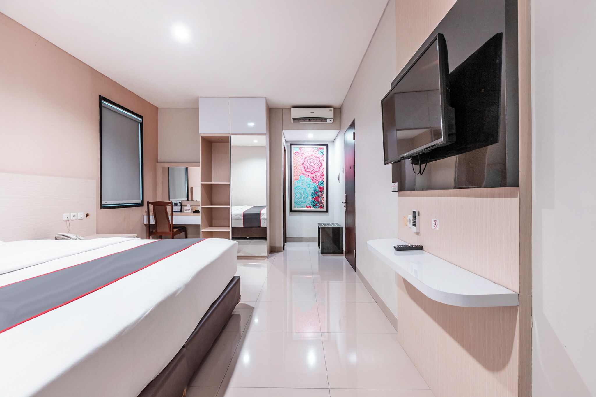 Une chambre d’hôtel moderne équipée d’un lit, d’un téléviseur fixé au mur, d’un bureau et d’une salle de bain.