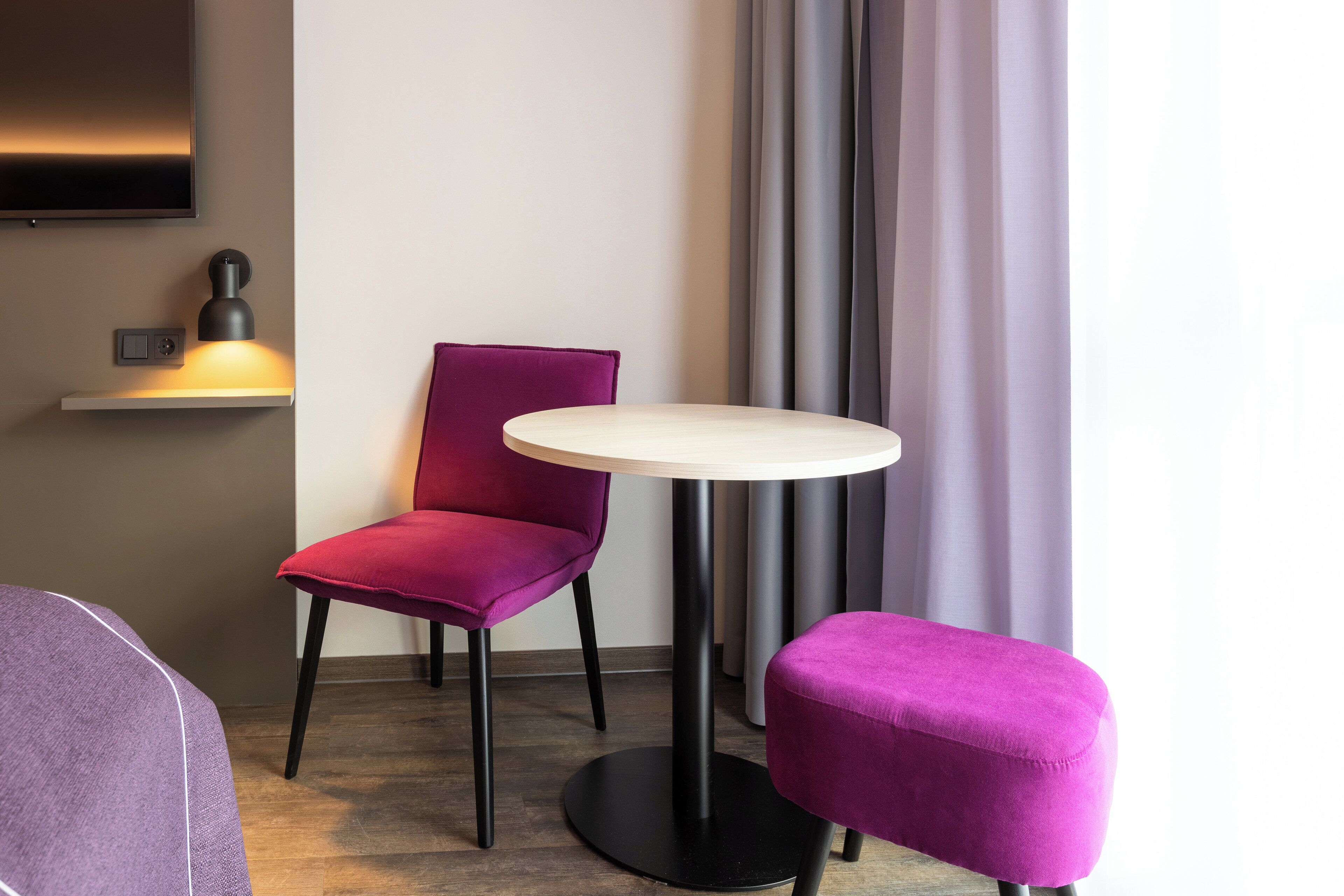 A modern room with a round table, a purple chair, and a small ottoman.