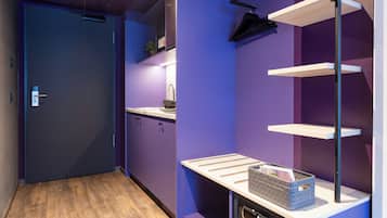 A modern kitchen with purple walls, wooden flooring, and built-in shelves.