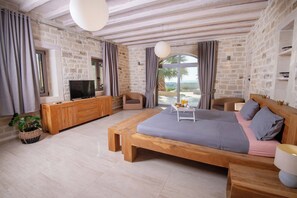 Ein Schlafzimmer mit einem großen Bett, Holzmöbeln, einem Fernseher und Blick ins Freie.