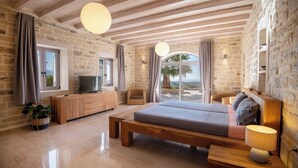 A spacious bedroom with a large bed, wooden headboard, a TV, and a view of the sea. - Villa Elia, By Hellocrete (Asteri village)