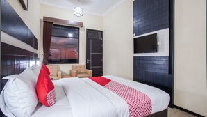 A hotel room with a large bed, a TV mounted on the wall, and a window with a view of the sky. - Capital O 887 Green Hill Hotel And Convention Center (Jombang)