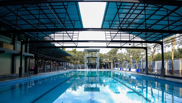 A swimming pool with a covered area, clear water, and a lifeguard tower. - Capital O 887 Green Hill Hotel And Convention Center (Jombang)