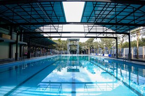 A swimming pool with a covered area, clear water, and a lifeguard tower. - Capital O 887 Green Hill Hotel And Convention Center (Jombang)