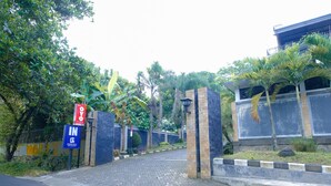 A gated entrance with a blue sign indicating 'IN GREEN KILL'. - Capital O 887 Green Hill Hotel And Convention Center (Jombang)