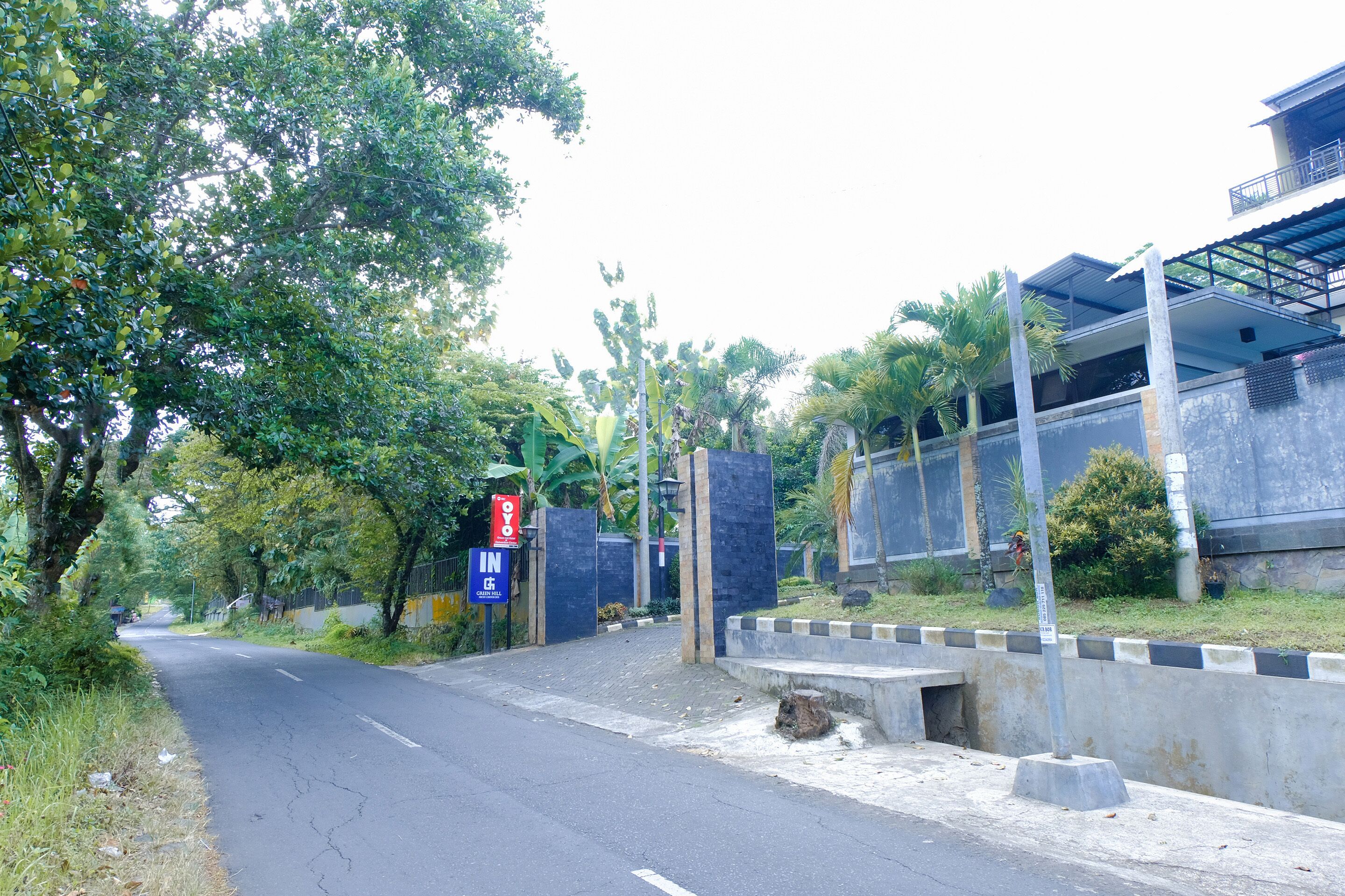 A road leading to a gated entrance with a blue sign indicating a parking area.