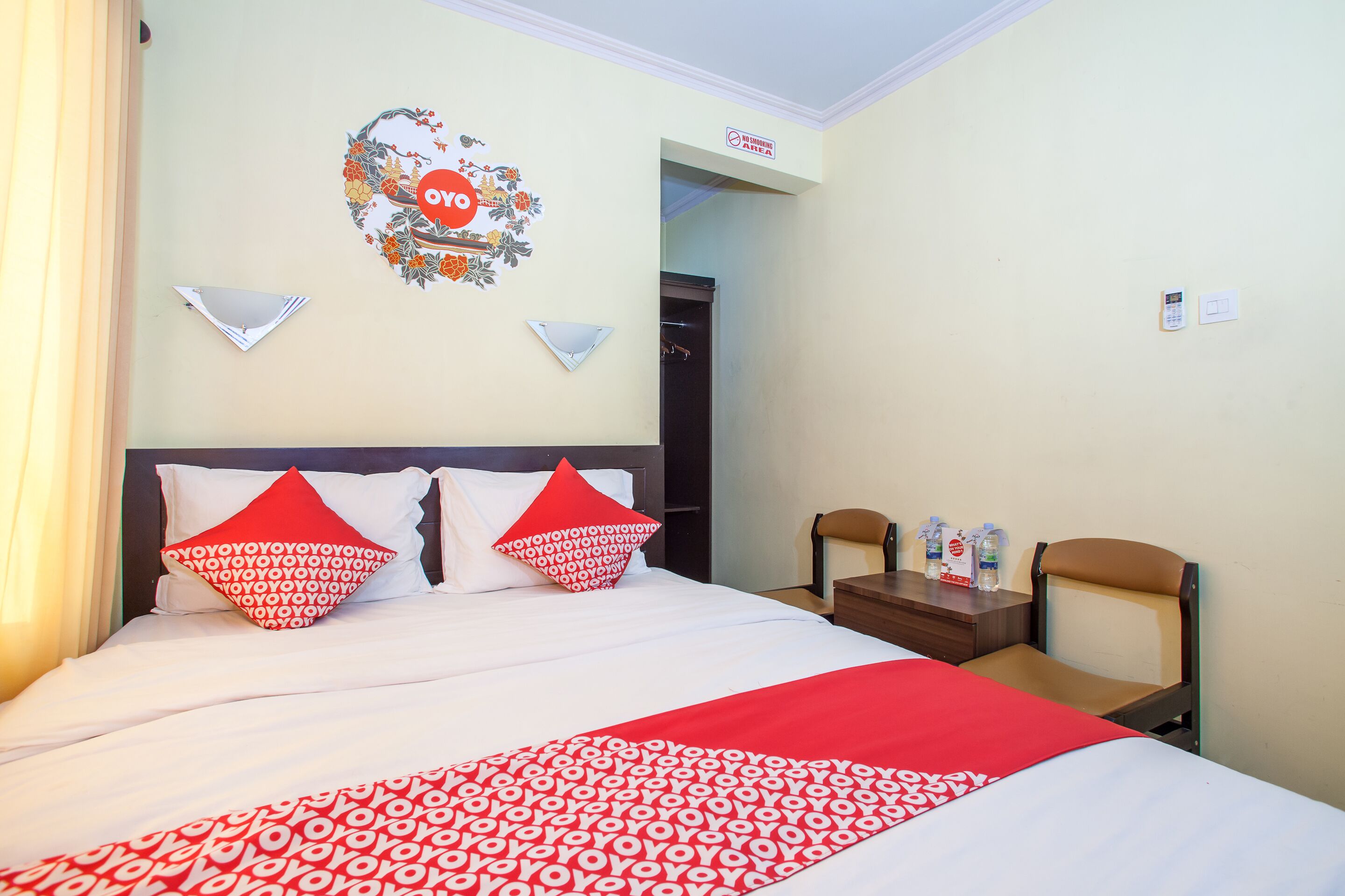 A hotel room with a bed, two chairs, a small table, and a wall decoration.