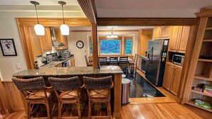 Una cocina con armarios de madera, encimera de granito y refrigerador de acero inoxidable.