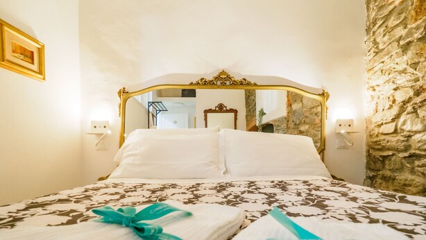 Une chambre d’hôtel avec un grand lit, un mur en pierre et un miroir au-dessus du lit.