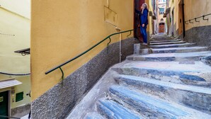 Un escalier étroit, avec un mur jaune d’un côté et des marches recouvertes de carreaux bleus de l’autre.