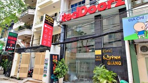 A hotel named RedDoorz with a visible signboard and a potted plant in front. - S79 Quynh Giang Airport Hotel (Ho Chi Minh City)