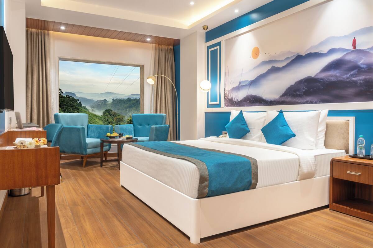 Une chambre d’hôtel moderne, dotée d’un grand lit, d’un bureau, d’une chaise et offrant une vue sur l’extérieur grâce à une grande fenêtre.