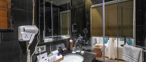 A modern bathroom with a large mirror, a sink, a hairdryer, and a shower.