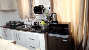 Une cuisine compacte équipée d’une cuisinière à gaz, d’une machine à café et d’un four à micro-ondes.