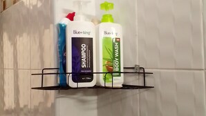 Une étagère de salle de bain avec des flacons de shampoing et de gel douche de la marque Blue+King.