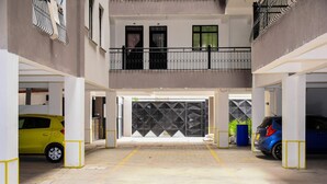 Eine mehrgeschossige Parkgarage mit zwei Autos, einem befahrbaren Eingangstor und einem Balkon mit Geländer.