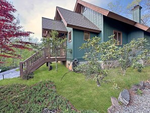 A two-story house with a wooden deck and a stone pathway leading to the entrance. - Bear Necessities - 2BR, sleeps up to 6, amazing view, hot tub + free Biltmore tix (Sylva)